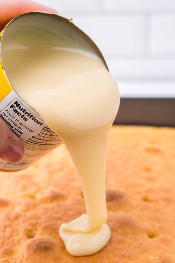 pouring condensed milk over the baked cake. 