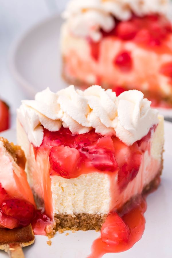 Close up shot of a slice of Strawberry cheesecake with a bite removed. 