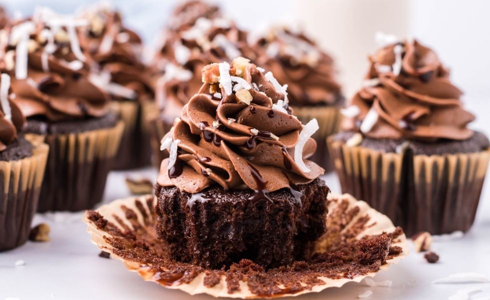 German Chocolate Cupcakes with one sitting unwrapped on a cupcake liner