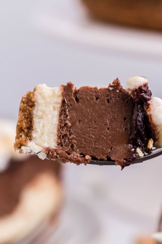 A piece of air fryer s'mores cheesecake on a fork showing the different layers.