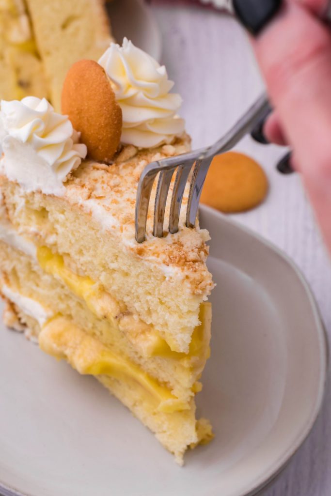 A slice of Banana Pudding Cake with a bite being removed. 