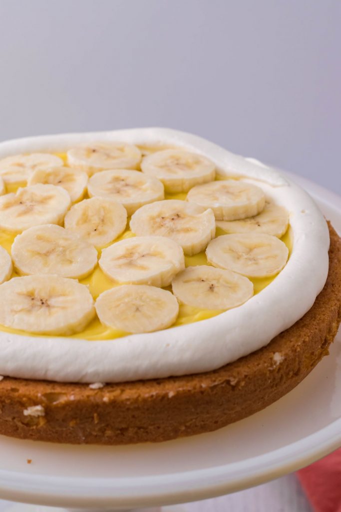 Topping the vanilla pudding with banana slices between cake layers.