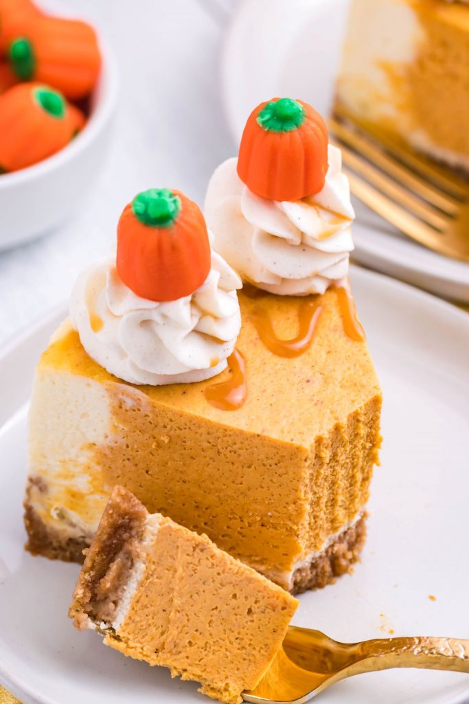A slice of Instant Pot Pumpkin Cheesecake on a white plate with a bite removed onto a gold fork.