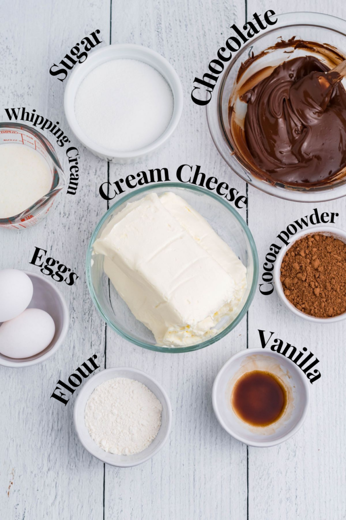 An overhead image of the following ingredients in bowl; 
Cream cheese, chocolate, cocoa powder, eggs, flour, vanilla, heavy whipping cream, and sugar 