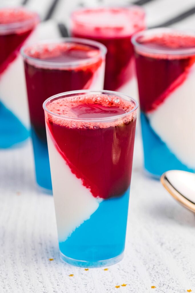 Tall shot glasses with red , white, and blue jello layer. 
