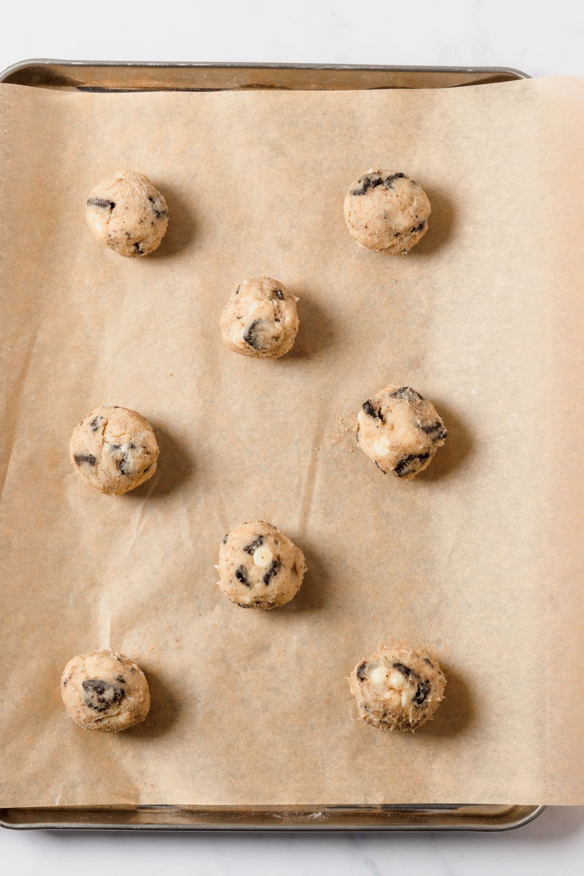 Overhead view of raw cookie dough balls on a baking sheet. 