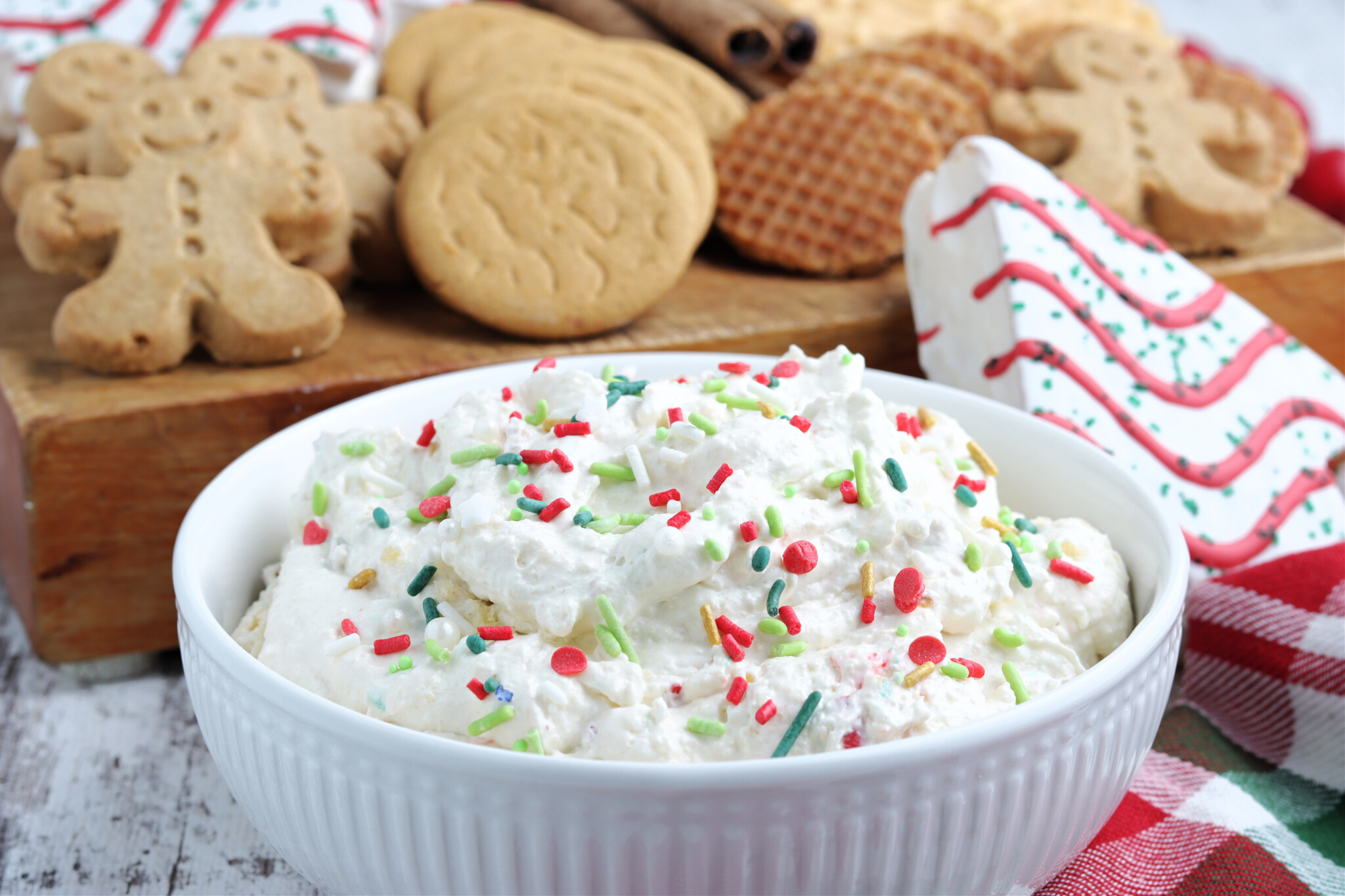 Straight on shot of Little Debbie Christmas Tree Cake Dip in a white bowl topped with holiday sprinkles. 