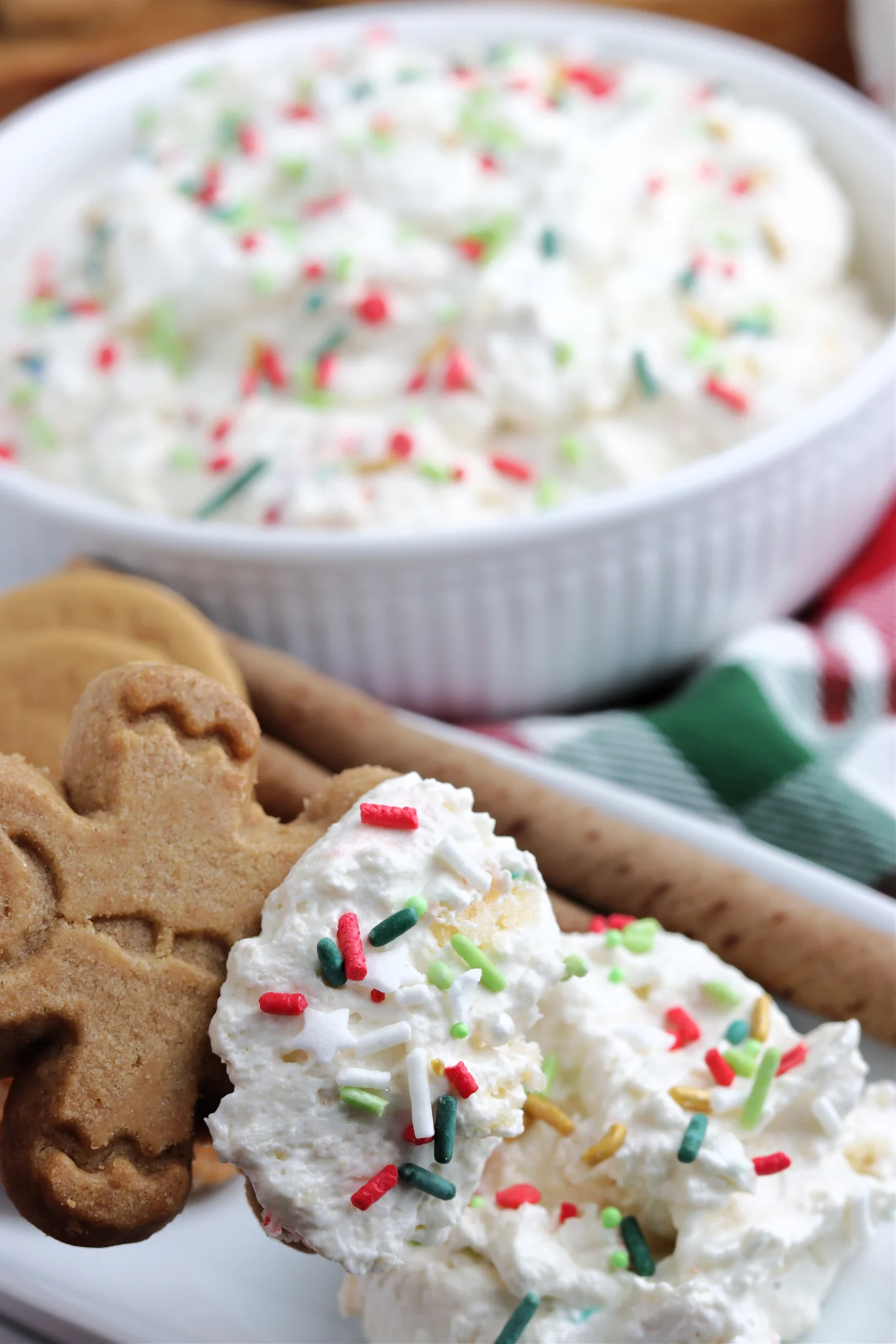 Christmas Tree Dip on a white plate with gingerbread cookies and a green and red cloth in the background. 