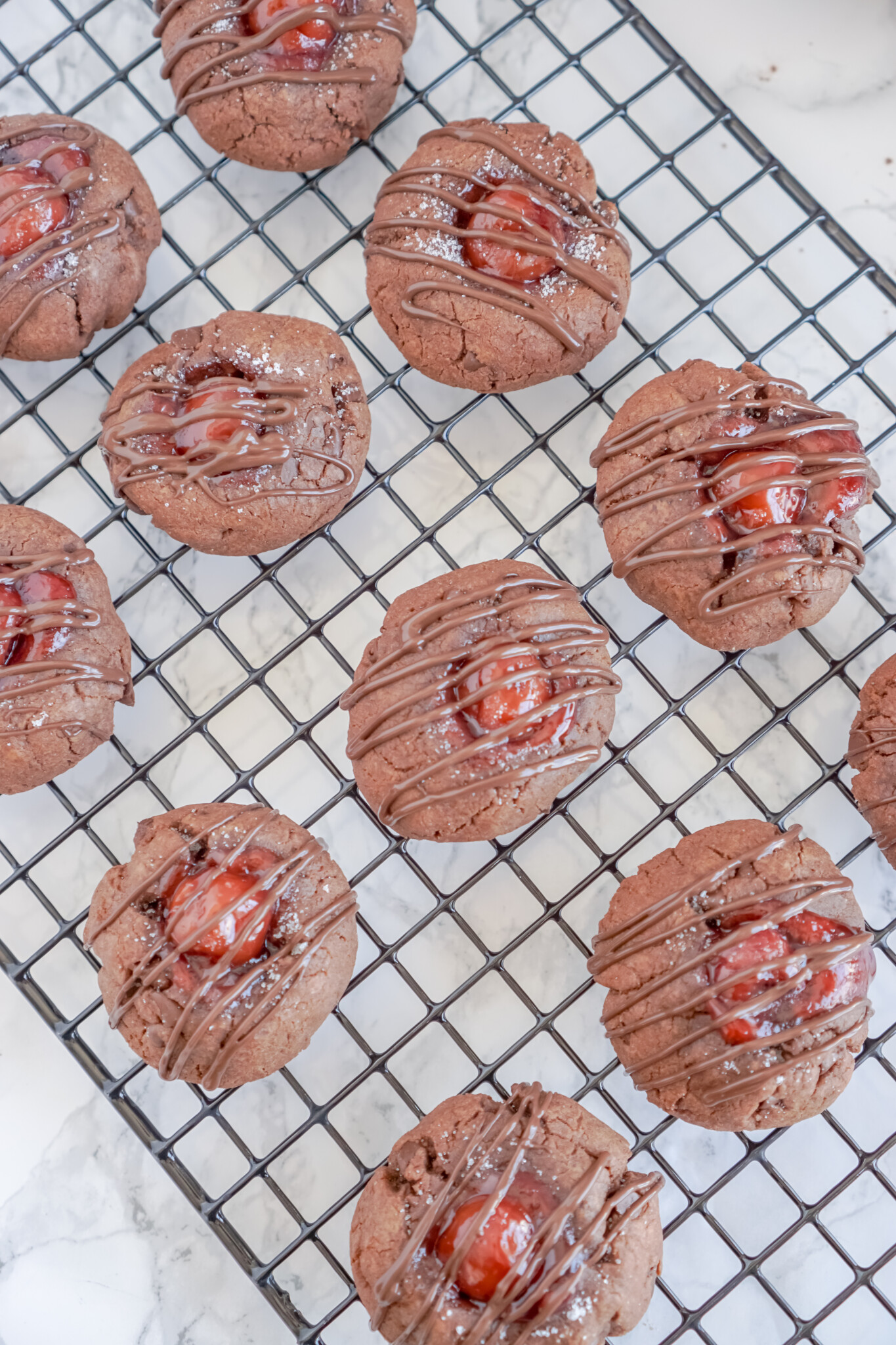 Overhead view of Chocolate Cherry Thumbprint Cookies on a black wire rack.