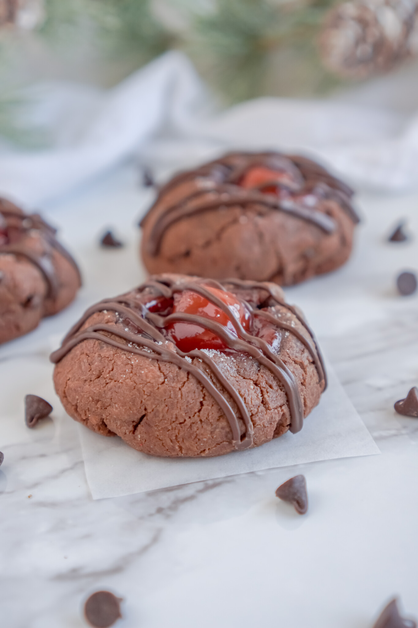 Front view of Chocolate Cherry Thumbprint Cookies on pieces of parchment paper.