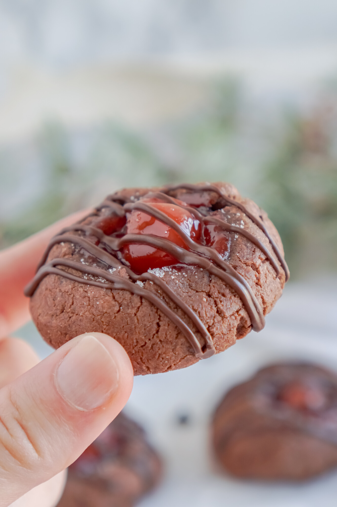 Front view of a Chocolate Cherry Thumbprint Cookie being held.