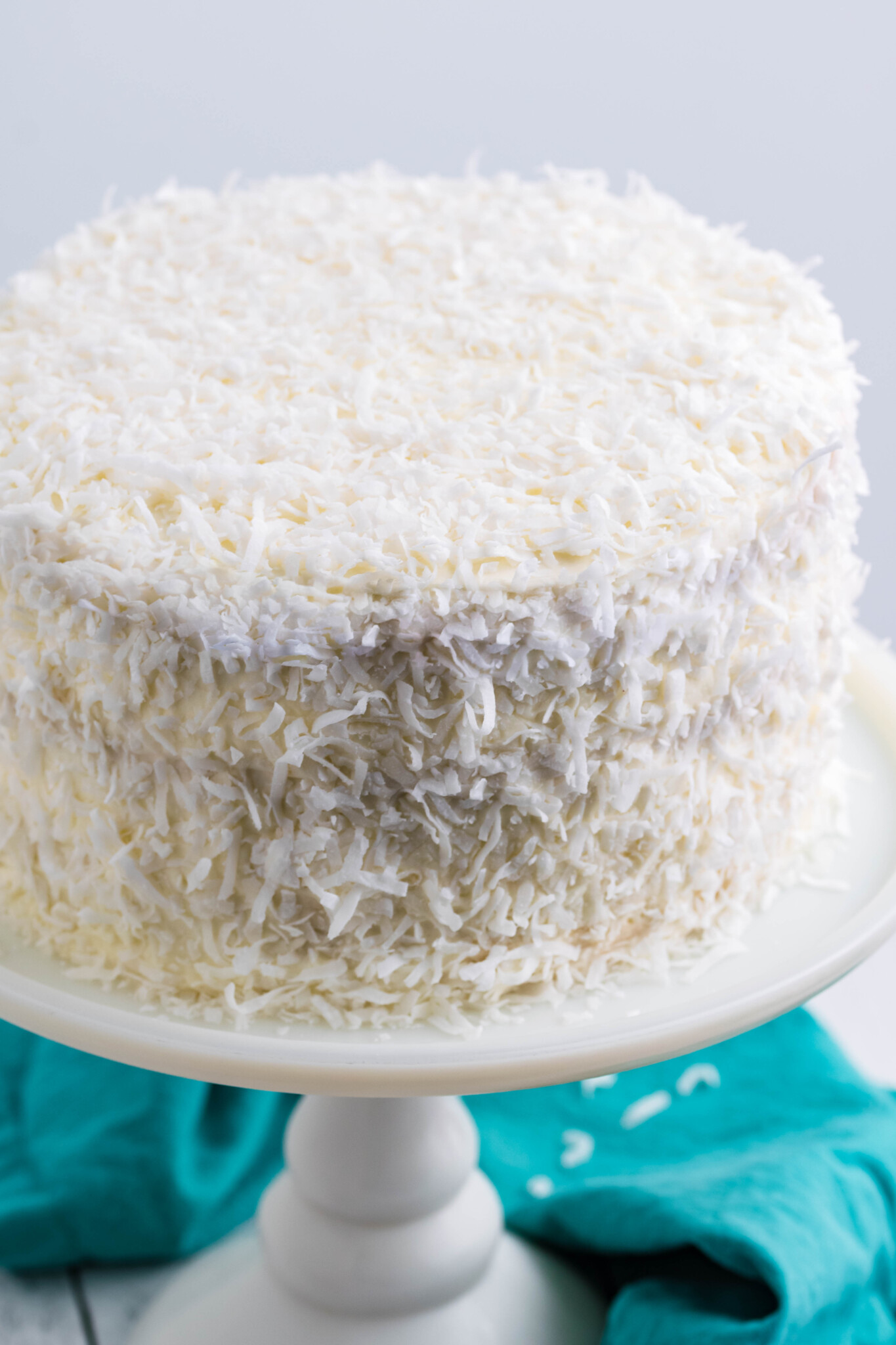 Front view of Coconut Cake on a white cake stand.