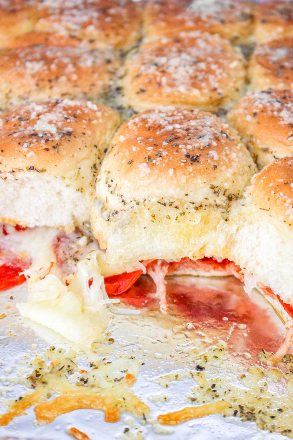 Pepperoni Pizza Sliders in a baking dish with a few of the sandwiches gone 