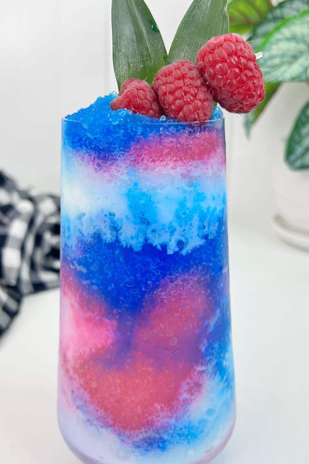 Blue Raspberry Pina Colada on a table with raspberries garnished at top of glass