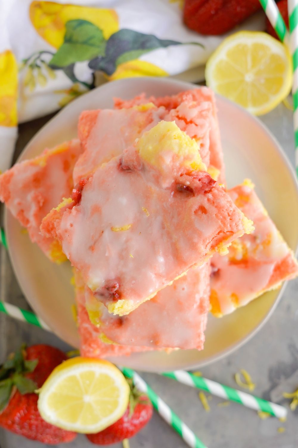 lemon strawberry bars stacked on plate with fresh fruit around the plate on table 