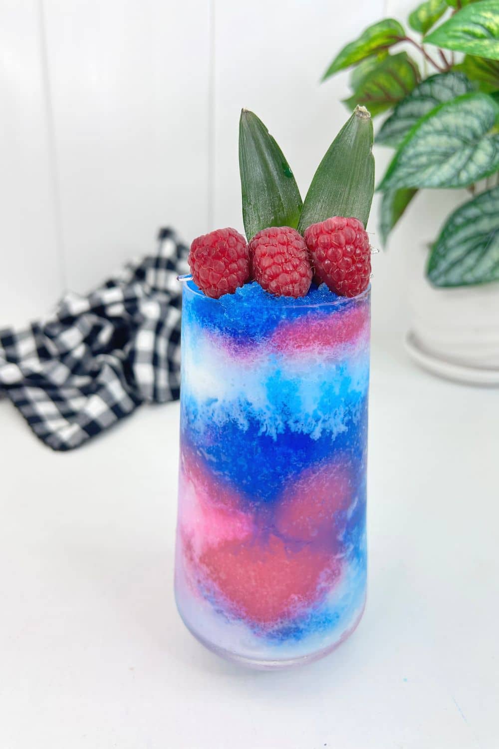 blue raspberry pina colada in a glas with a black checkered napkin behind on table 