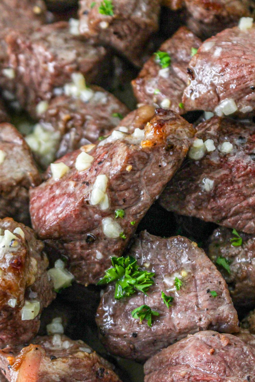 steak bites with garlic and parsley stack on a plate 