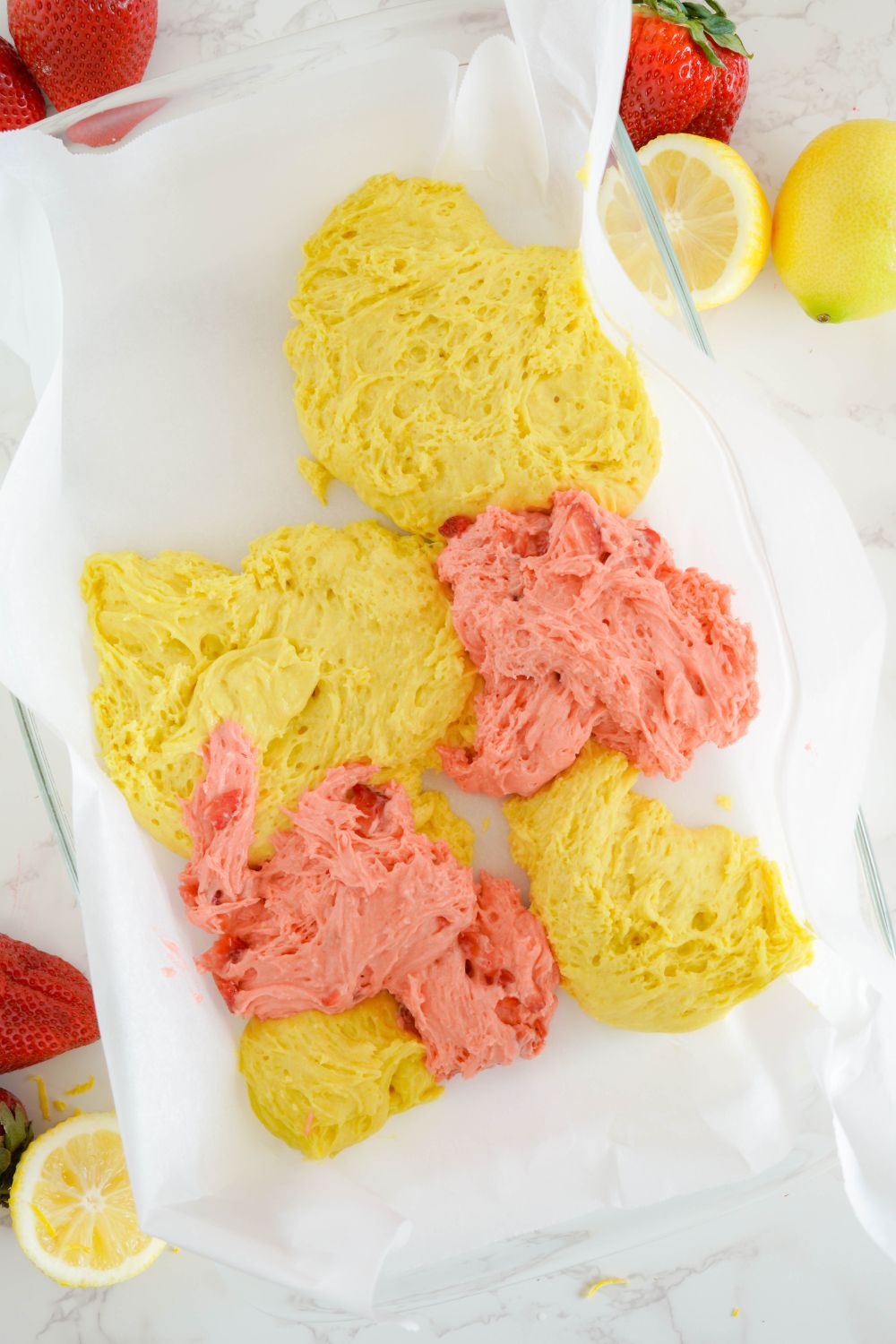 drops of pink and yellow blondie batter in a baking dish 